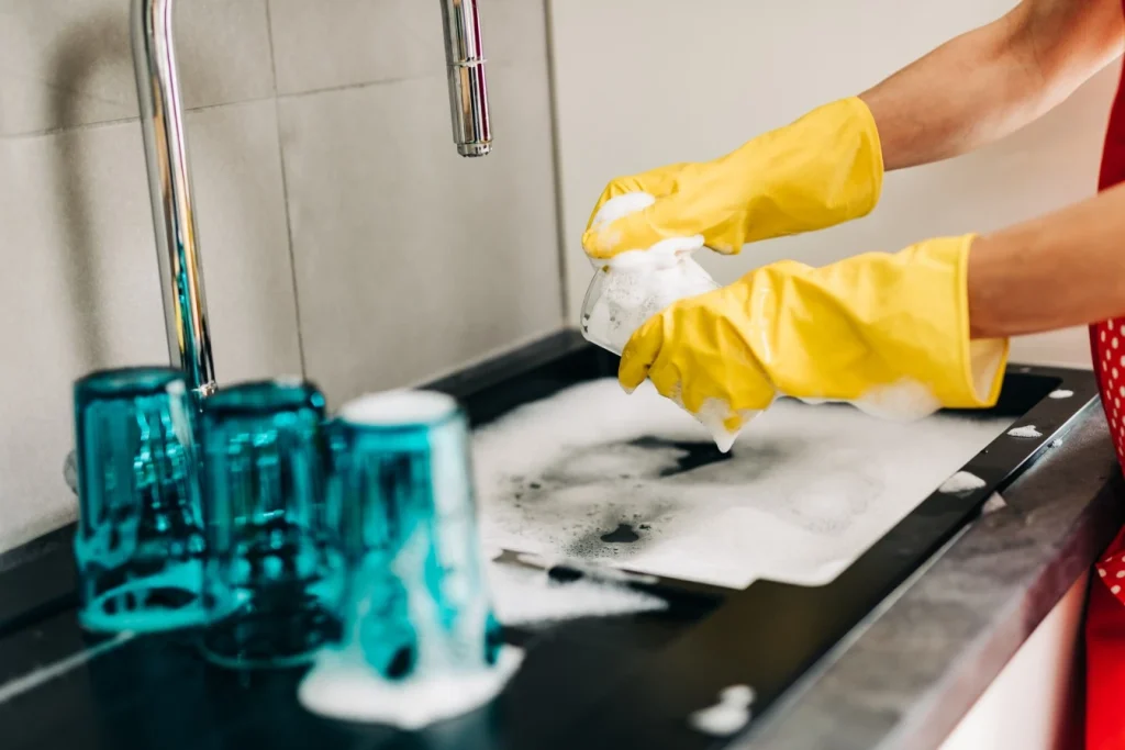 Close up of person doing dishes in kitchen sink