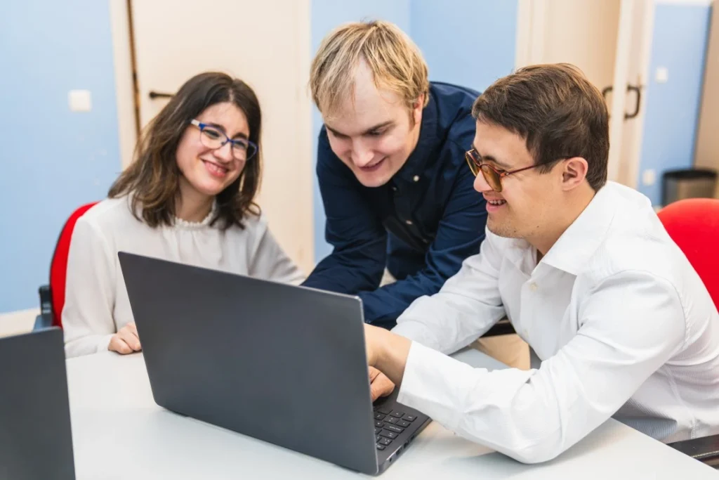 Group of disabled friends gathered around laptop